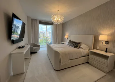 A white bedroom with a tv and a bed.