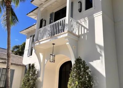 A white house with palm trees and a balcony.