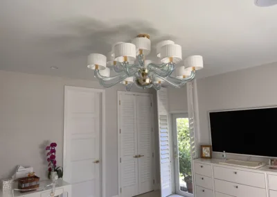 A bedroom with a white dresser and tv.